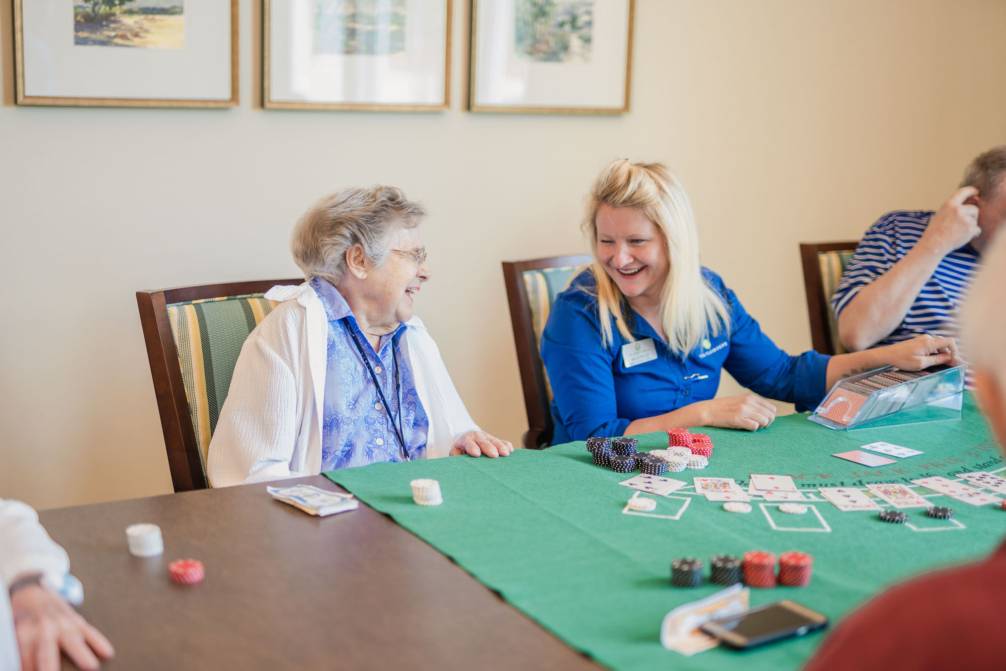 The Claiborne at Brickyard Crossing senior resident and employee playing cards in the game room